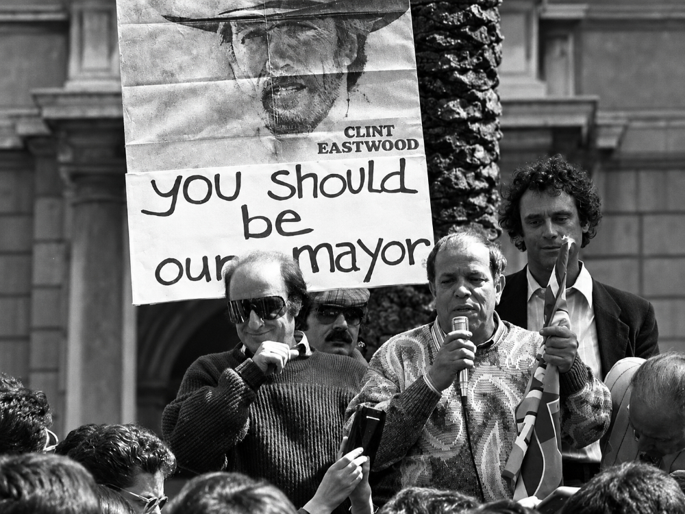 Giorgio Bracardi durante una manifestazione pubblica, accanto a un cartello dedicato a Clint Eastwood